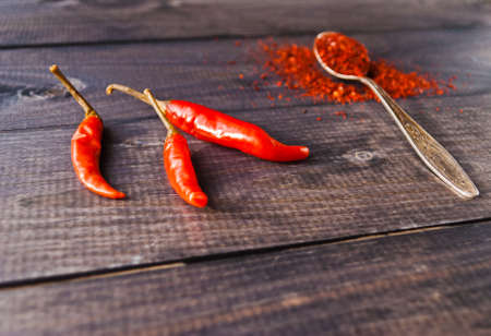 Full tea spoon of ground chili pepper and raw red chiliesの写真素材