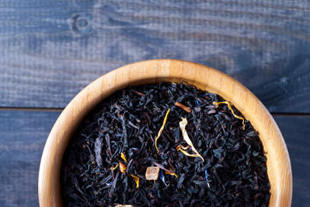 Dried tea leaves and flowers in bamboo bowl on wooden background. Close upの写真素材