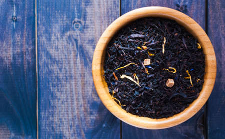 Dried tea leaves and flowers in bowl on blue shabby wooden background. Copy spaceの写真素材