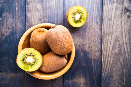 Kiwi fruit in a bowl on rustic wooden background. Empty space for textの写真素材