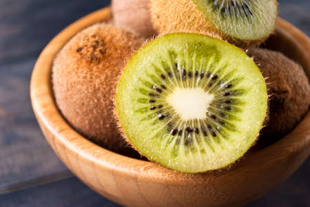 Group of kiwi fruit in a brown bowl on rustic wooden backgroundの写真素材
