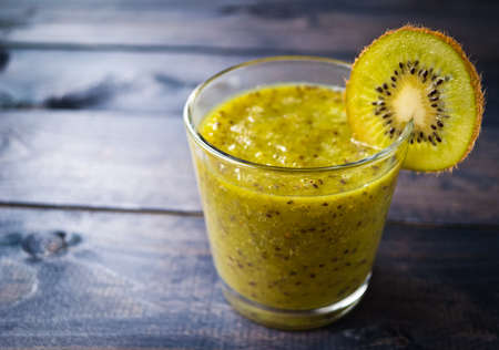 Fresh green smoothie from kiwi fruit and one slice of fruit on the edge of glass. Copy spaceの写真素材