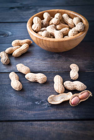 Bowl of peanuts with shell on wooden backgroundの写真素材