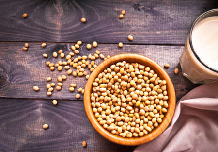 Glass of soy milk and full bowl of soy beans on wooden background. Top viewの写真素材