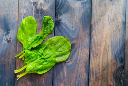Bright green spinach leaves on wooden background