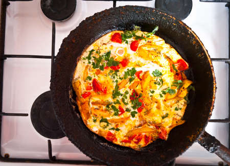Homemade fritatta with tomatoes, parsley and fried potato in the old cast iron frying pan. Top viewの写真素材