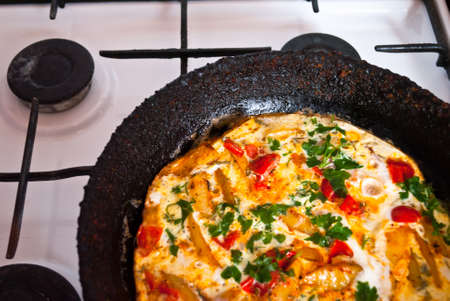 Homemade fritatta with tomatoes, parsley and fried potato in the old cast iron frying pan. Close upの写真素材