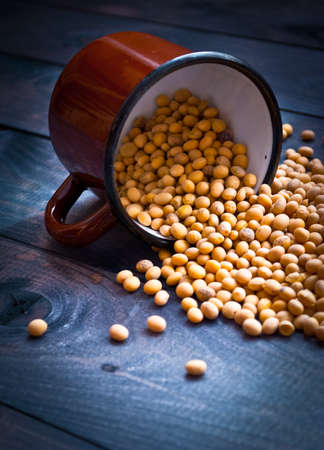 Raw soy beans in the brown metal cup on wooden backgroundの写真素材