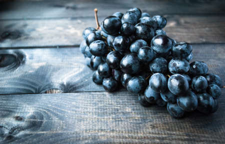 Bunch of black grapes on a shabby wooden background. Copy spaceの写真素材