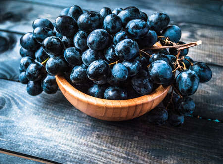 Bunch of black grapes in a bamboo bowlの写真素材