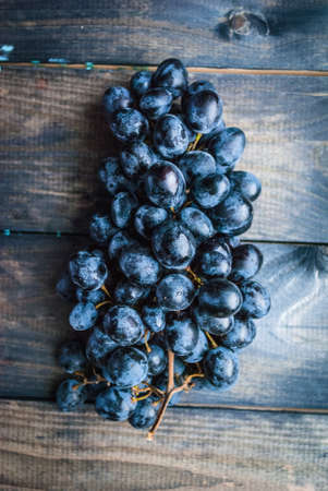 Bunch of black grapes on a wooden background. Top viewの写真素材