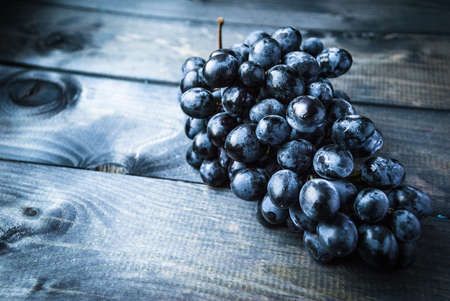 Bunch of black grapes on a blue wooden backgroundの写真素材