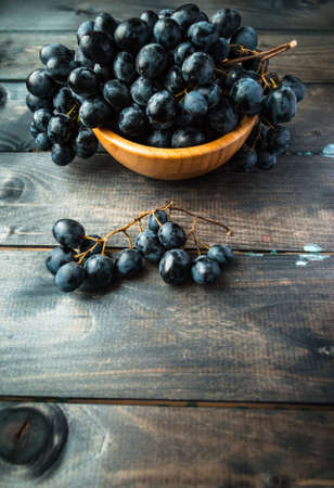 Bunches of black grapes in a bamboo bowl. Copyspaceの写真素材