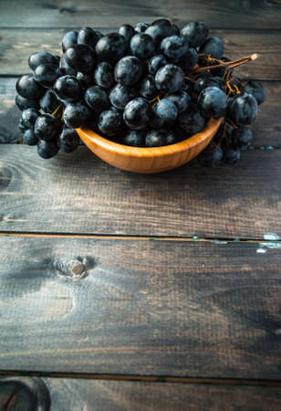 Bunch of black grapes in a bowl. Copy spaceの写真素材