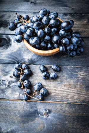 Bunches of black grapes in a bamboo bowl. Copyspaceの写真素材