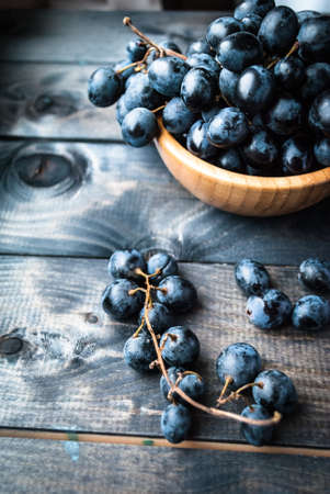 Bunch of black grapes in a bamboo bowl. Verticalの写真素材