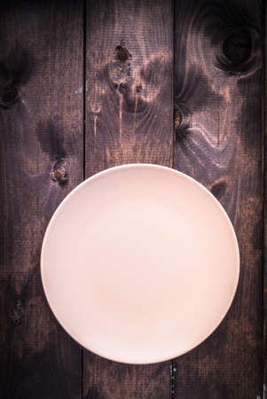 Empty gray plate on brown wooden background. Top viewの写真素材
