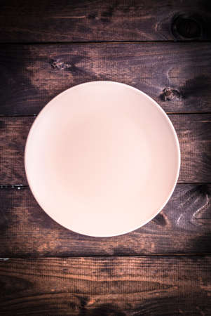 Empty gray plate on a brown wooden background. Top viewの写真素材