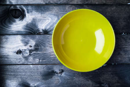 Empty yellow soup plate on a blue wooden background. Space for a textの写真素材