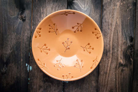 Empty dark beige bowl with flower pattern on a wooden backgroundの写真素材
