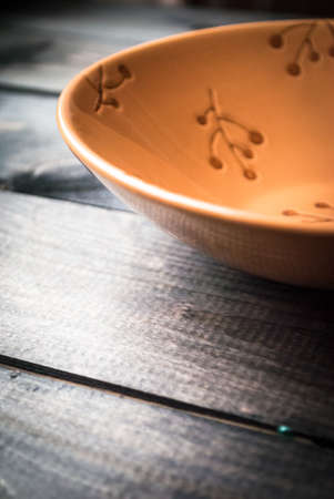 Empty beige soup plate with flower pattern on a wooden background. Space for a textの写真素材