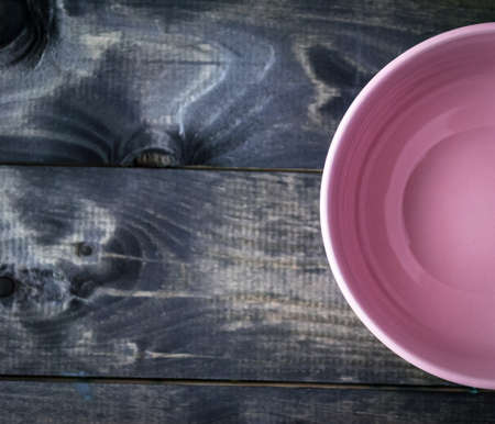 Empty pink bowl on a varnished wooden background. Top viewの写真素材