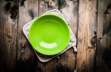 Empty green bowl lies on a gray potholder with wooden backgroundの写真素材