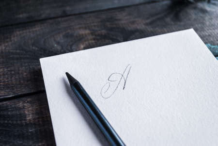 Pencil lying on open notebook with lettering on top page