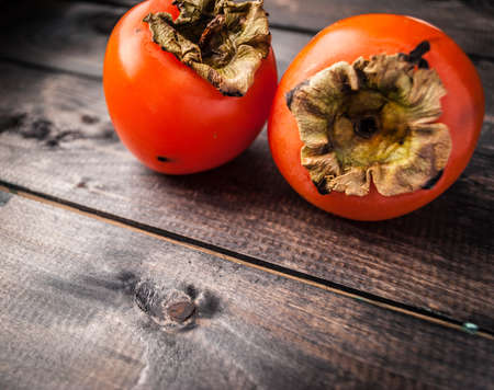 Ripe whole persimmons on a shabby wooden backgroundの写真素材