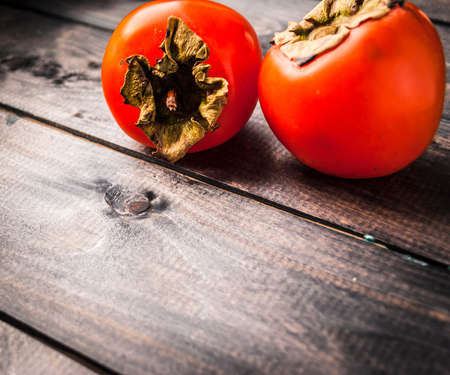Ripe whole persimmons on a rustic wooden backgroundの写真素材
