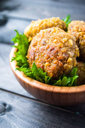 Fried chickpea falafel and leaves of green salad on a bamboo bowlの写真素材