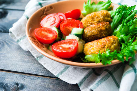 Fried chickpea falafel and fresh vegetable salad in a ceramic bowl