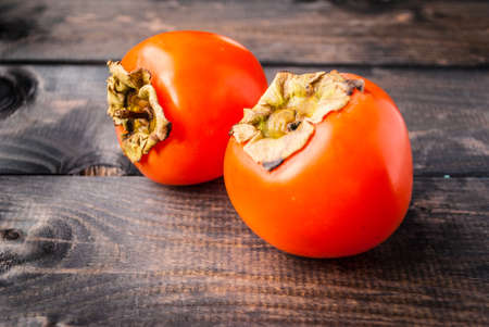 Ripe whole persimmons on a wooden background in rustic styleの写真素材
