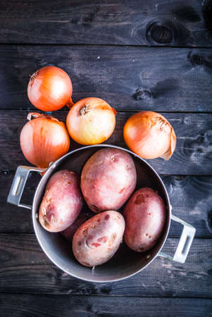 Raw potatoes in a pan and onions beside. Top view. Place for textの写真素材