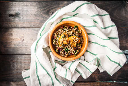 Bamboo bowl of boiled buckwheat with spinach and red beans on the kitchen table and striped towel. Copyspaceの写真素材