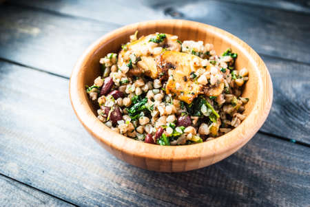 Bamboo bowl of boiled buckwheat, spinach and red beans with slices of fried champignon on the topの写真素材