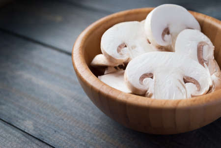 Sliced raw white champignon mushrooms in a bowl, space for textの写真素材
