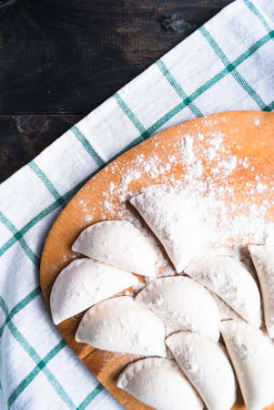 Wooden cutting board with raw dumplings on a striped towel. Top viewの写真素材