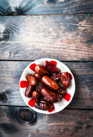 Saucer of date fruits on a wooden background, top viewの写真素材