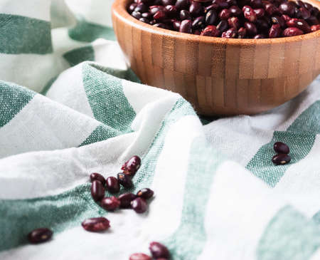 Dried red kidney beans in a bamboo bowl and on a kitchen towel, close upの写真素材