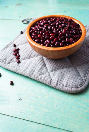 Dried red beans in bamboo bowl on a grey potholderの写真素材