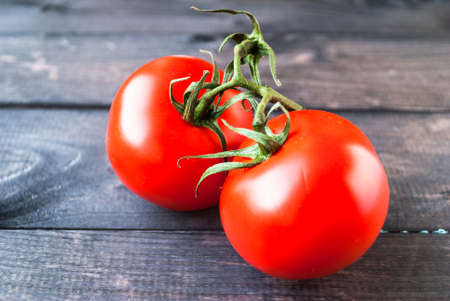 Fresh red ripe tomatoes on a branch on a wooden background, close upの写真素材
