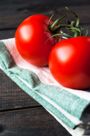 Fresh red ripe tomatoes on a branch on a kitchen towel, close upの写真素材