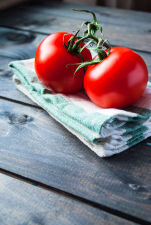 Fresh red ripe tomatoes on a branch on a kitchen towelの写真素材