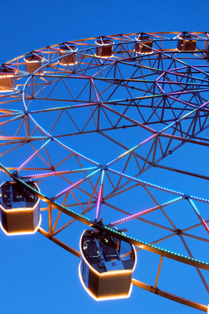 Traditional ferris wheel with colorful carriages at a night sky. Amusement park.