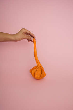 Hand holding orange pumping on pink background. Aesthetic.の写真素材