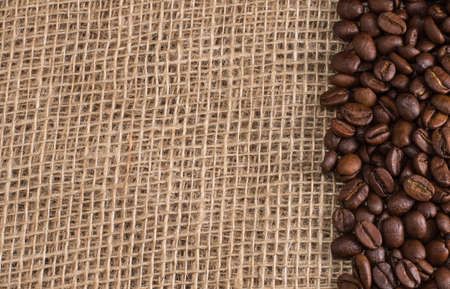 Coffee beans lying on sackcloth with space for textの写真素材