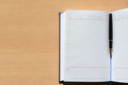Notebook with pen on a wooden desk in the office, copy Spaceの写真素材