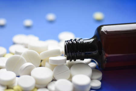 Round tablets arranged abstract isolated on blue color background. Pills for design. Concept of health, healthy lifestyle. Copy space for advertisement. Tablets are poured from a tubeの写真素材