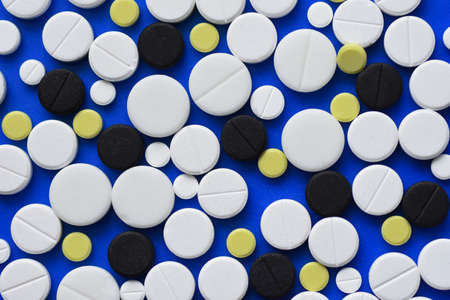 Round tablets arranged abstract isolated on blue color background. Pills for design. Concept of health, healthy lifestyle. Copy space for advertisement.の写真素材